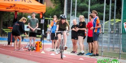 Sports day activity, girl riding a bicycle while Aloha cheers her on.