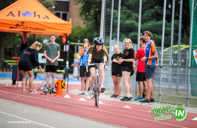 Sports day activity, girl riding a bicycle while Aloha cheers her on.